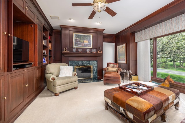 living room with ceiling fan, crown molding, light colored carpet, and a high end fireplace