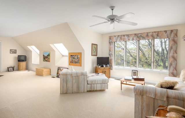 living room featuring vaulted ceiling with skylight, ceiling fan, and carpet