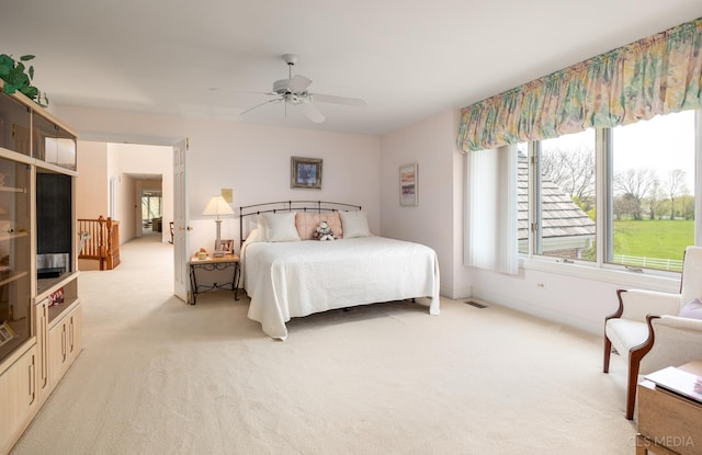 carpeted bedroom featuring ceiling fan and multiple windows