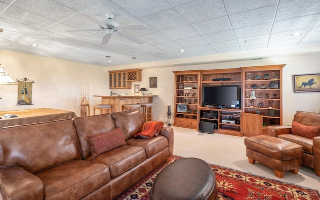 carpeted living room featuring built in features, bar area, and ceiling fan