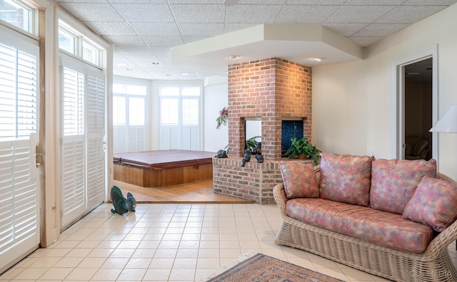 tiled living room featuring brick wall, a wealth of natural light, and a fireplace