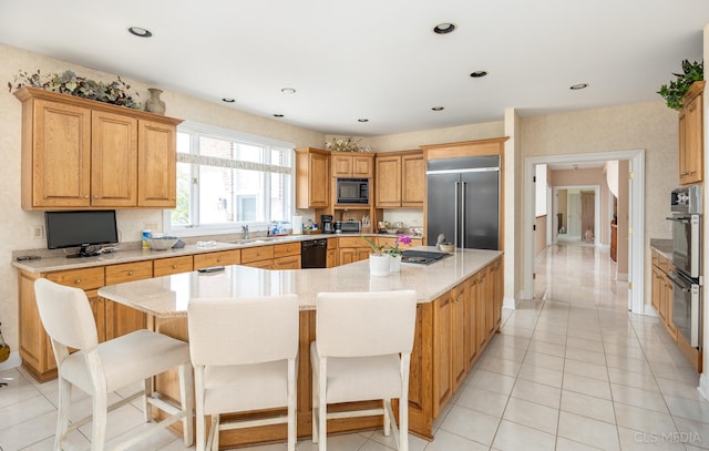 kitchen with light tile floors, light stone counters, a kitchen island, a kitchen breakfast bar, and black appliances