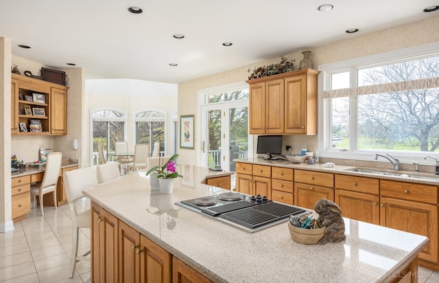 kitchen with sink, light tile floors, a kitchen island, light stone countertops, and a kitchen bar