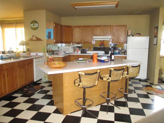 kitchen featuring light tile floors, a kitchen breakfast bar, white appliances, and sink