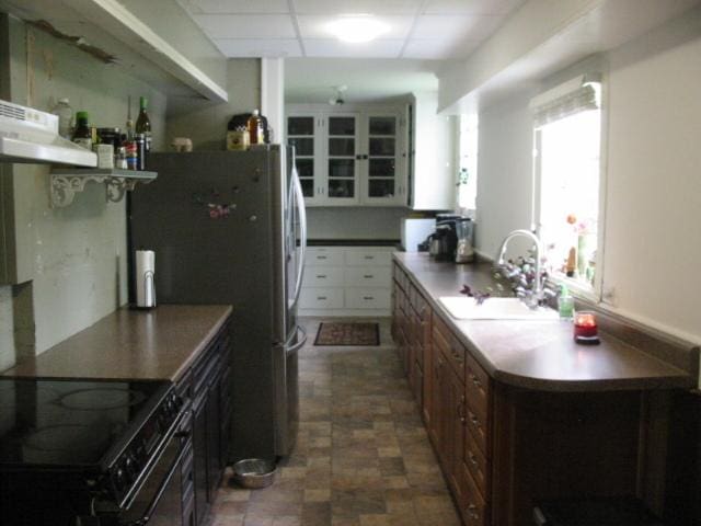 kitchen with white cabinets, a drop ceiling, sink, and dark tile flooring