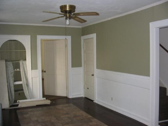 empty room with ceiling fan, dark hardwood / wood-style floors, and crown molding