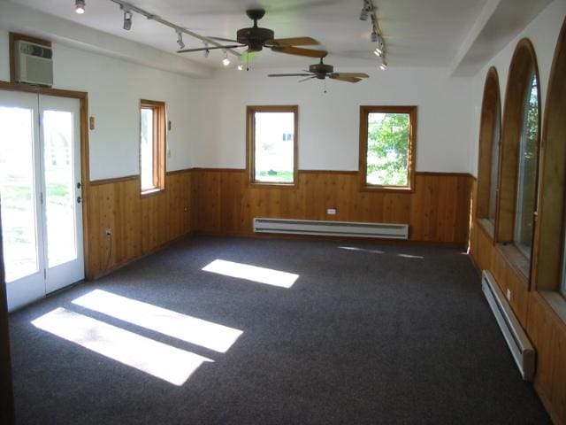 unfurnished room featuring track lighting, a baseboard radiator, and a wealth of natural light