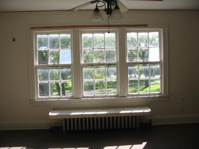 unfurnished room featuring an inviting chandelier, a wealth of natural light, and radiator heating unit