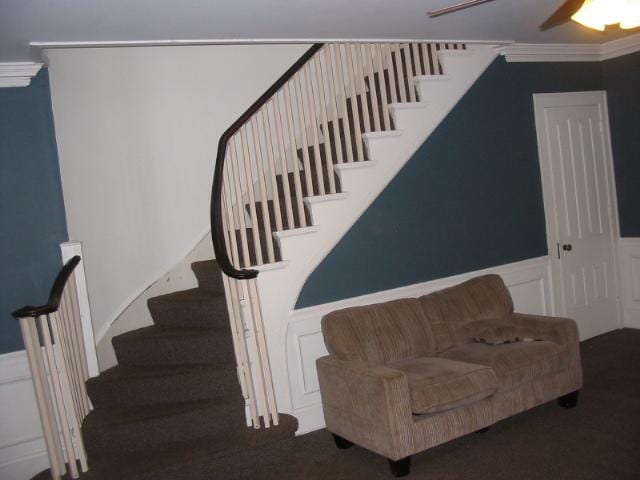 staircase featuring ceiling fan and crown molding