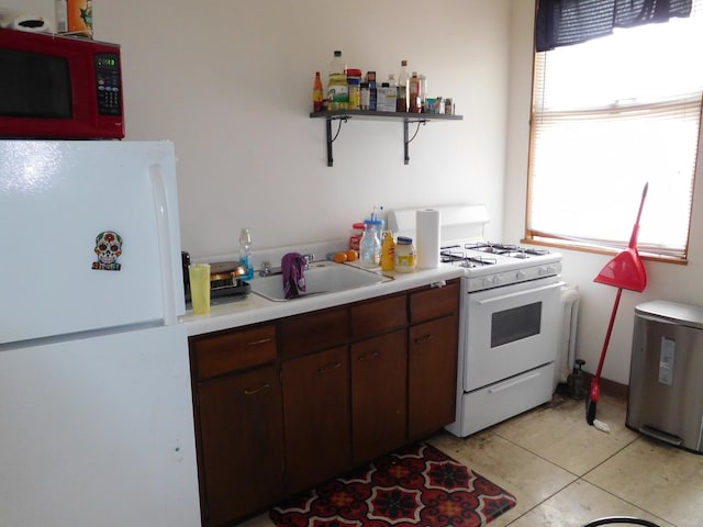 kitchen featuring light tile flooring, sink, white appliances, and dark brown cabinets