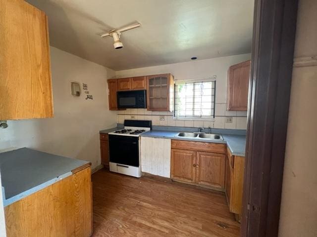 kitchen with dark wood-type flooring, white range with gas stovetop, track lighting, sink, and tasteful backsplash