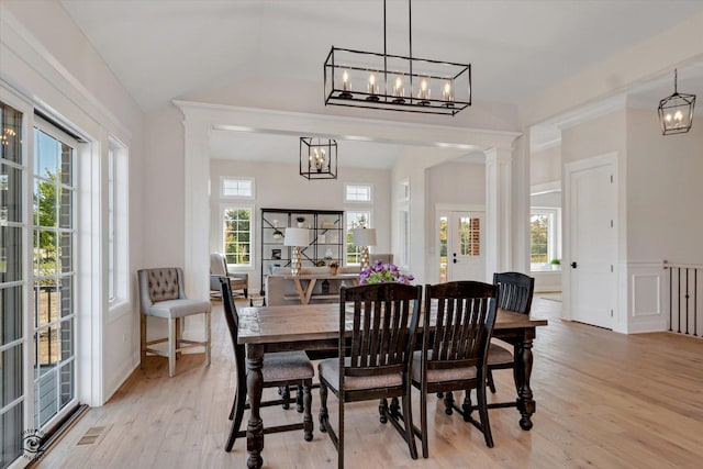 dining room featuring decorative columns, a chandelier, a wealth of natural light, and light wood-type flooring