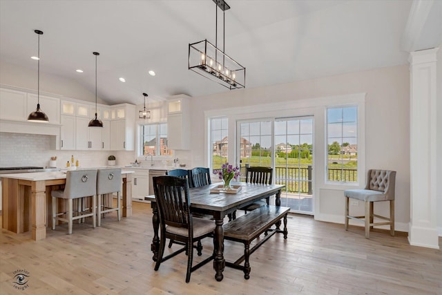 dining space with light hardwood / wood-style flooring, sink, lofted ceiling, and an inviting chandelier