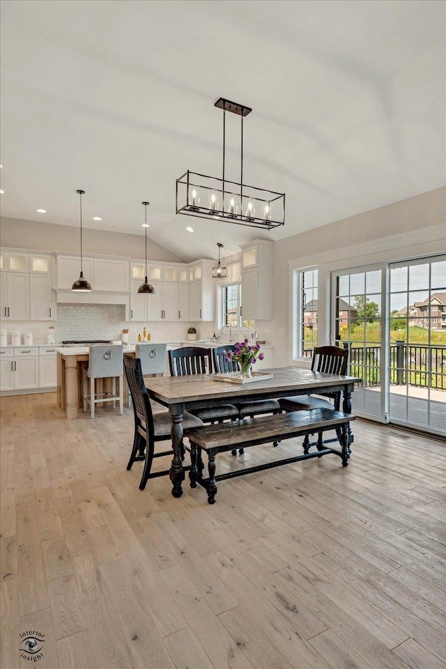 dining space featuring vaulted ceiling, light hardwood / wood-style flooring, and an inviting chandelier