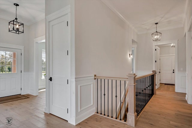 entrance foyer featuring crown molding, a notable chandelier, and light hardwood / wood-style flooring