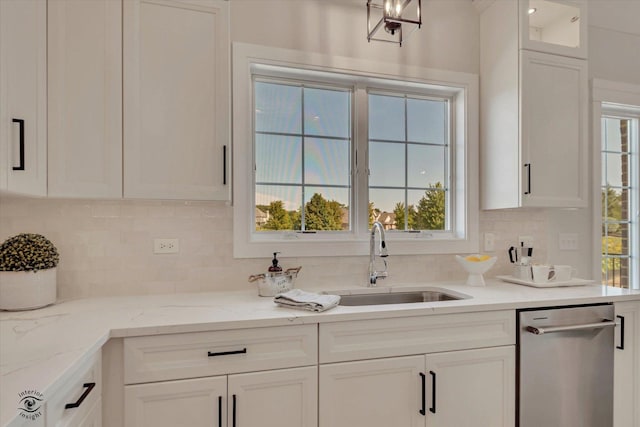 kitchen with sink, light stone counters, white cabinets, stainless steel dishwasher, and tasteful backsplash