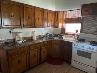 kitchen featuring sink, tasteful backsplash, white gas stove, and light tile flooring