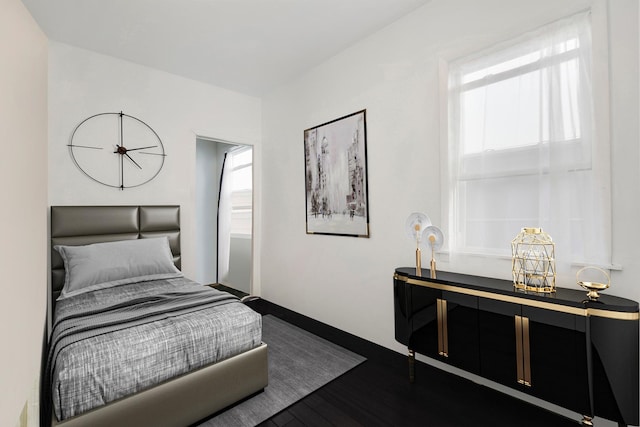 bedroom with multiple windows and dark wood-type flooring