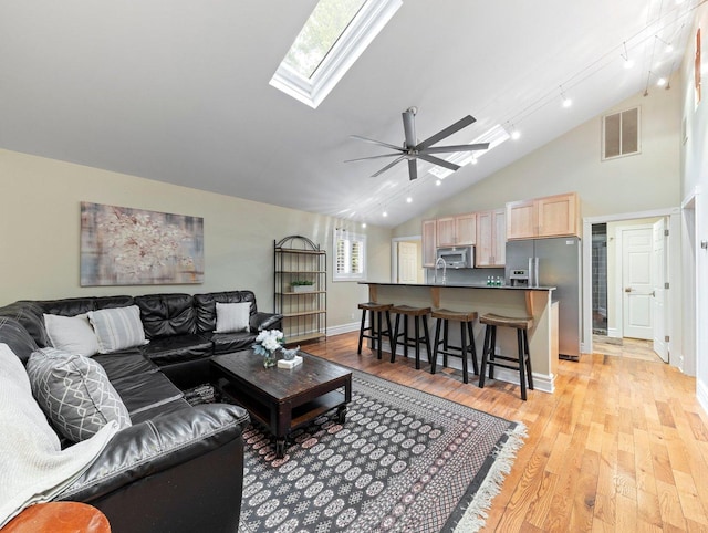 living room featuring a skylight, light hardwood / wood-style floors, ceiling fan, and track lighting