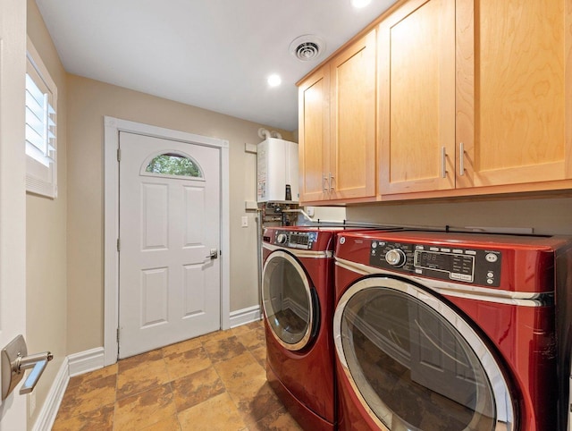 washroom featuring cabinets, washing machine and clothes dryer, water heater, and dark tile flooring