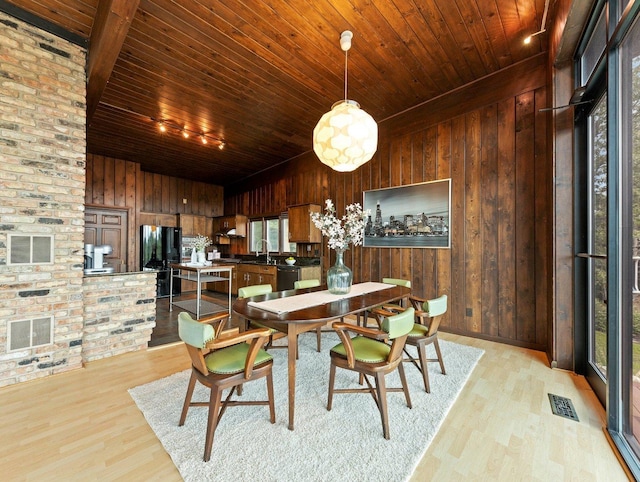 dining room featuring brick wall, sink, light hardwood / wood-style floors, wooden ceiling, and wood walls