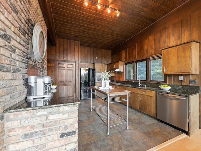 kitchen with brick wall, dark stone counters, dark hardwood / wood-style flooring, dishwasher, and sink