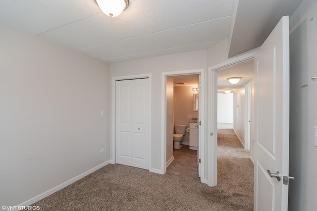 unfurnished bedroom with a closet, light colored carpet, and ensuite bath