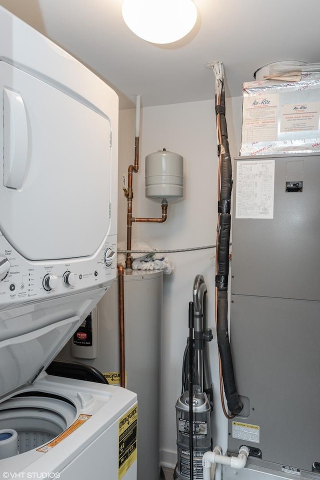 washroom with stacked washer and clothes dryer, heating utilities, and water heater