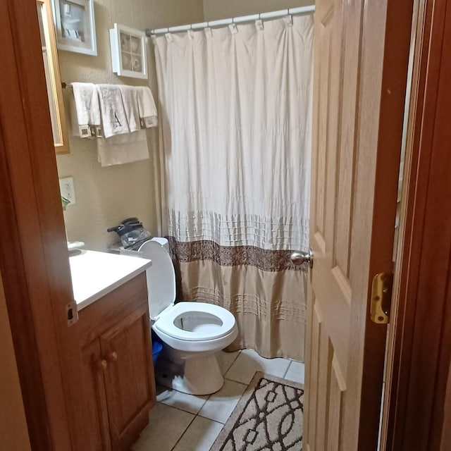 bathroom with toilet, vanity, and tile flooring