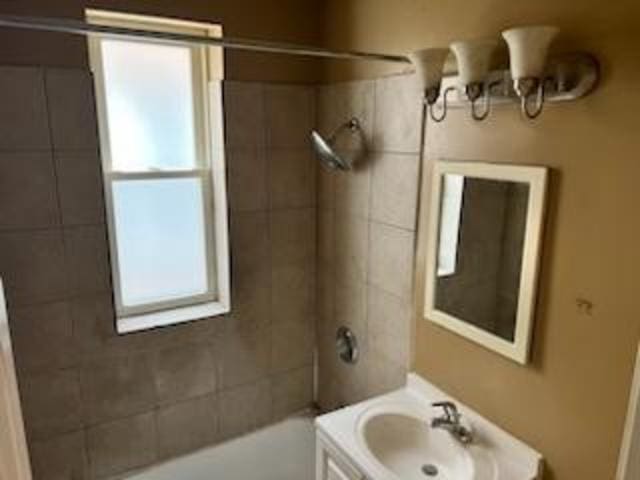 bathroom with tiled shower / bath combo and vanity