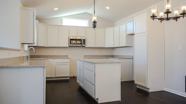 8357 Dylan Dr, Merrillville, IN 46410 - kitchen with light stone counters, stainless steel microwave, dark wood-type flooring, vaulted ceiling, and a sink