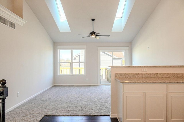 8357 Dylan Dr, Merrillville, IN 46410 - unfurnished living room featuring ceiling fan, lofted ceiling with skylight, carpet, and baseboards