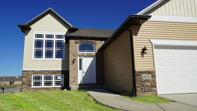 view of front of property with an attached garage, stone siding, and a shingled roof