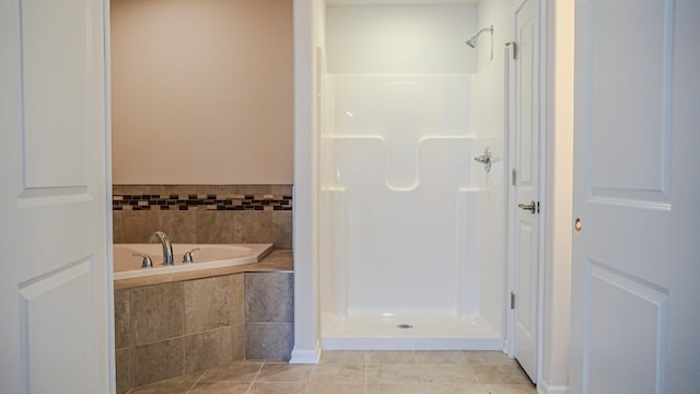 bathroom with tile patterned flooring, a garden tub, and a shower stall