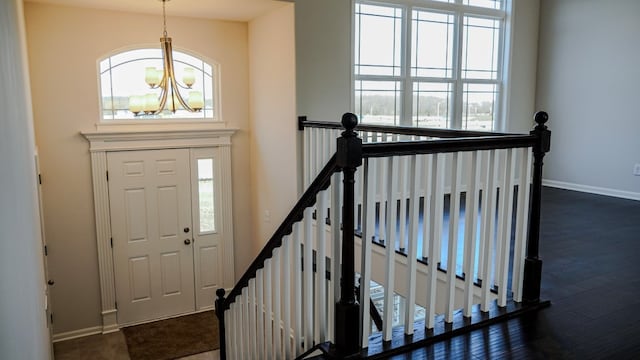 entrance foyer with dark wood-style floors, a chandelier, a healthy amount of sunlight, and baseboards