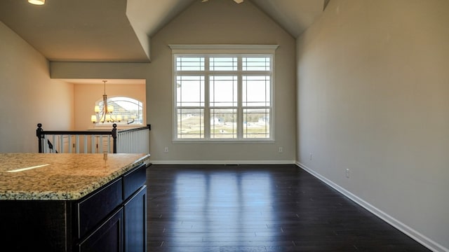 interior space featuring baseboards, dark wood-style floors, light stone countertops, vaulted ceiling, and a notable chandelier