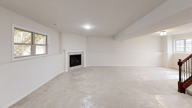 unfurnished living room with baseboards, stairway, and a tiled fireplace