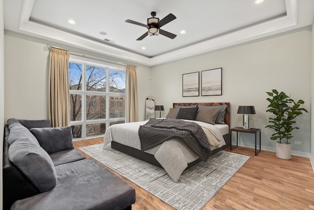 bedroom with a raised ceiling, light hardwood / wood-style floors, and ceiling fan