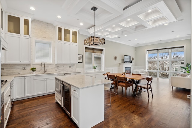 kitchen with coffered ceiling, dark wood-type flooring, a center island, pendant lighting, and sink