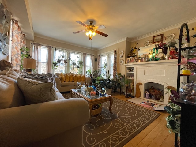 living room featuring ornamental molding, ceiling fan, light wood-type flooring, and a brick fireplace