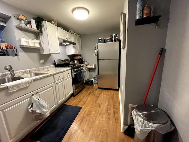 kitchen featuring light hardwood / wood-style floors, white cabinetry, gas range, stainless steel fridge, and sink