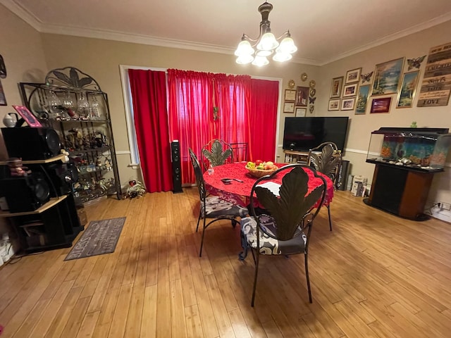 dining space with a notable chandelier, light wood-type flooring, and ornamental molding