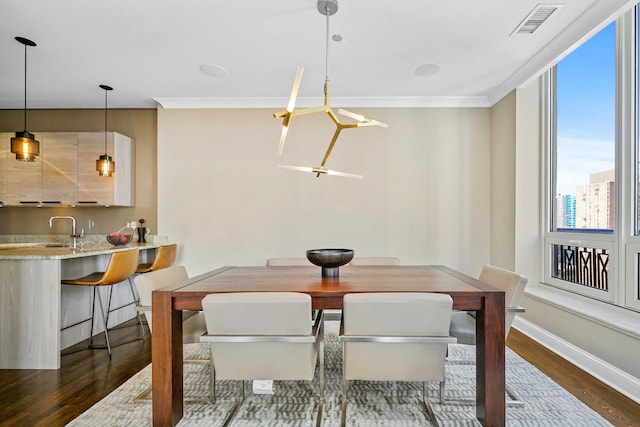 dining area with crown molding, dark hardwood / wood-style floors, and sink