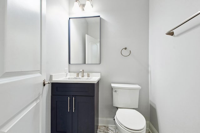 bathroom with marble finish flooring, toilet, vanity, and baseboards