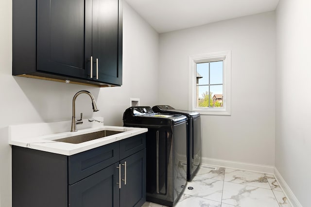 laundry area featuring cabinet space, washing machine and clothes dryer, light marble finish floors, and baseboards