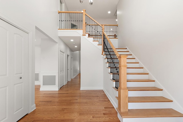 stairway with wood finished floors, a high ceiling, and recessed lighting