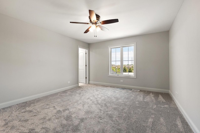 carpeted spare room featuring a ceiling fan and baseboards