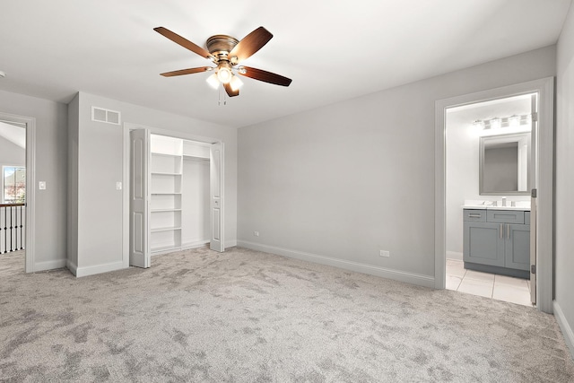 unfurnished bedroom with light carpet, baseboards, a closet, a ceiling fan, and ensuite bathroom