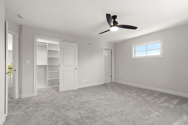 unfurnished bedroom featuring carpet floors, baseboards, a spacious closet, and ceiling fan