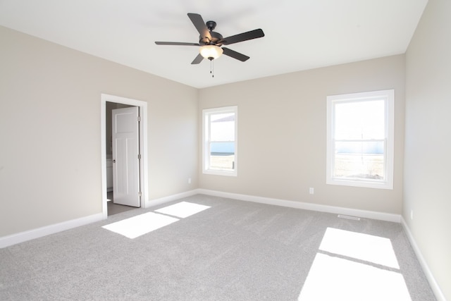 carpeted empty room featuring ceiling fan and a wealth of natural light